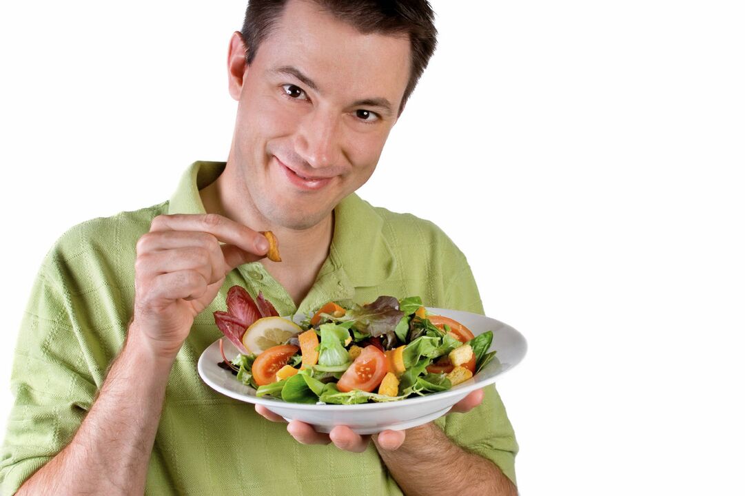 El hombre come ensalada de verduras para potenciar